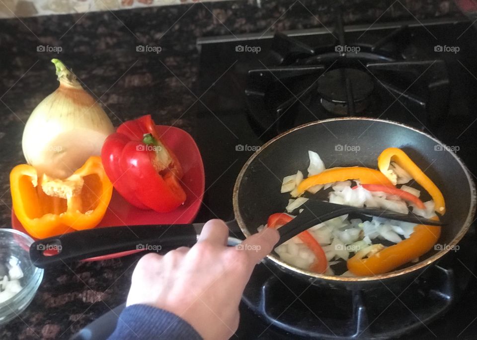 Sautéing and Cooking onions and bell peppers, Preparing vegetables on the stove. 