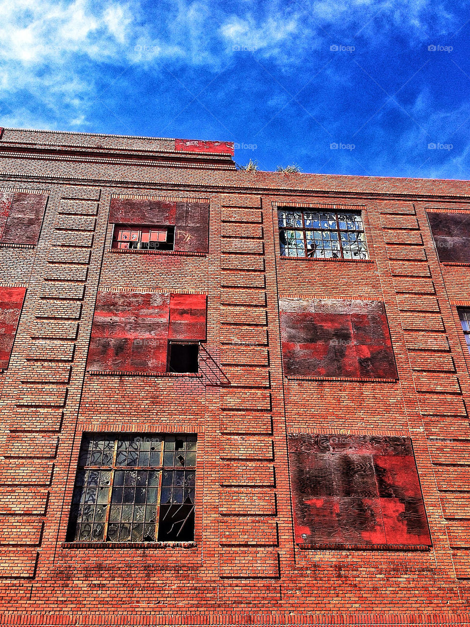 Broken glass windows of an abandoned red brick warehouse on a San