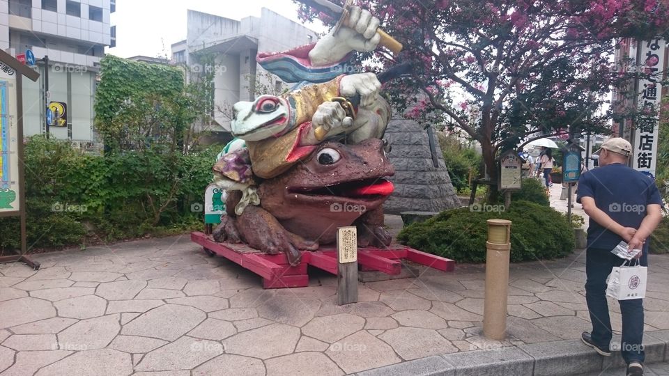 Man looking at sculpture of frog in park