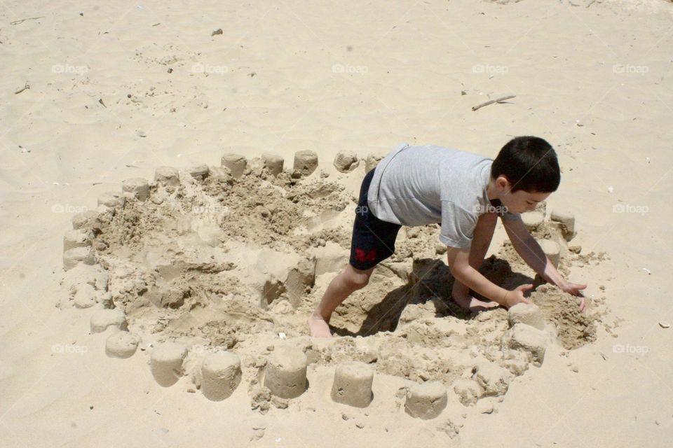 Kid build many sand palaces at the beach in a circle 