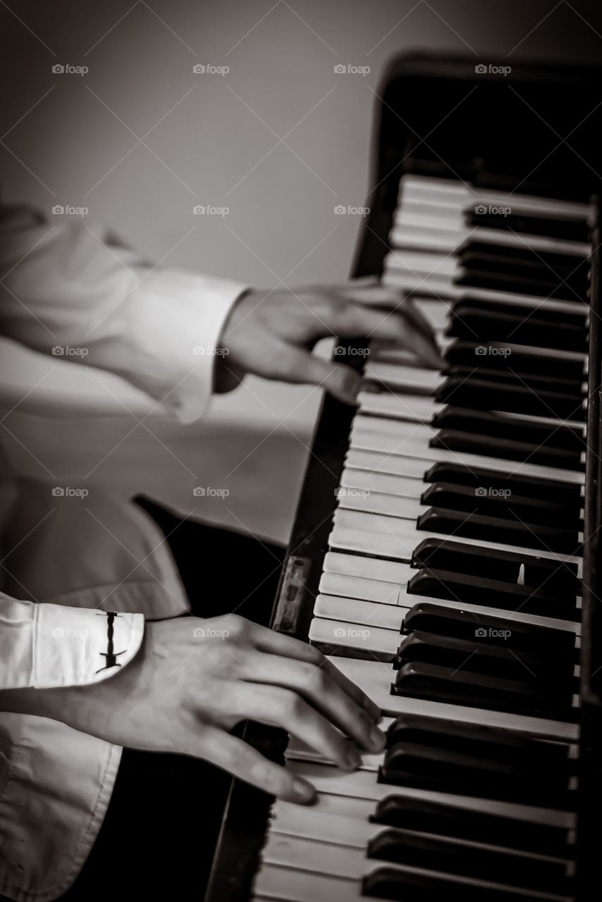 close-up hands in the frame playing the piano black and white photo
