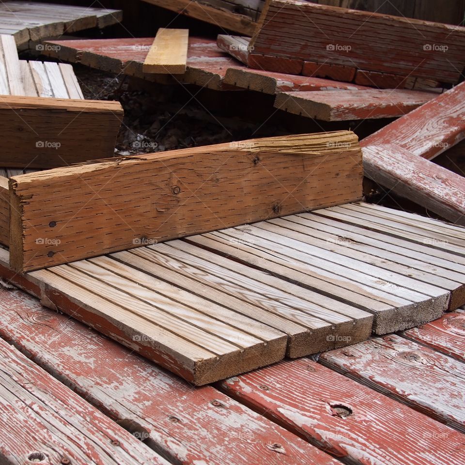 A cluttered stack of wooden pallets with worn red paint and texture. 
