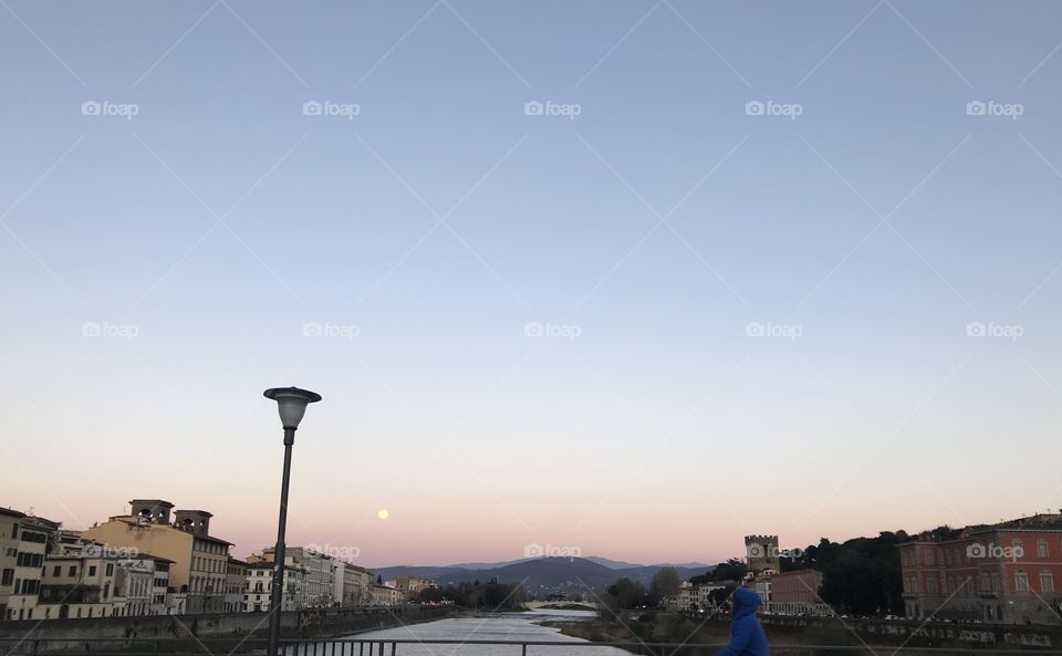 The view from Ponte alle Grazie, with the sunset and a super close full moon, in Florence, Italy.