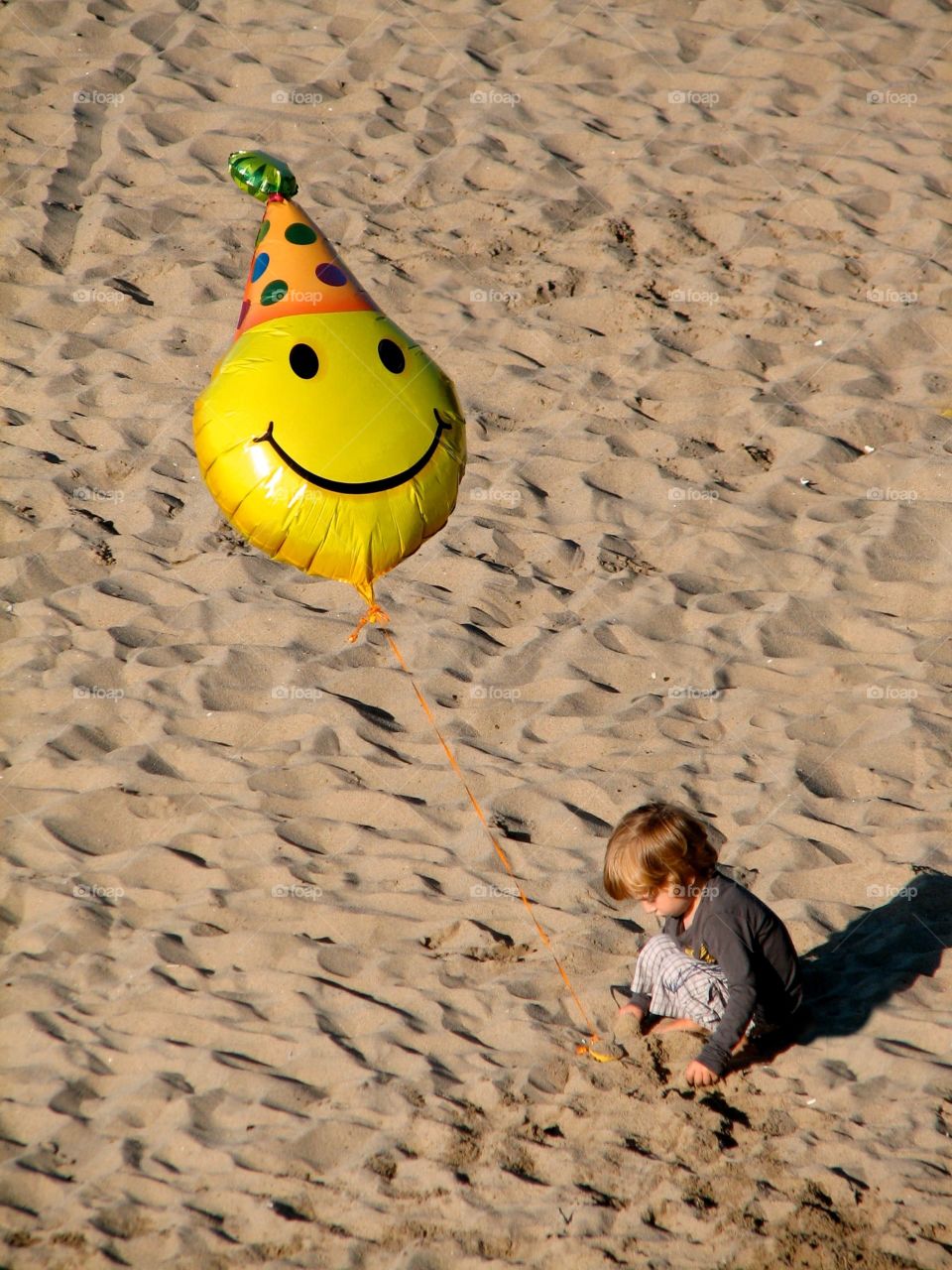 Birthday balloon. Child with smiley-face birthday balloon on the beach