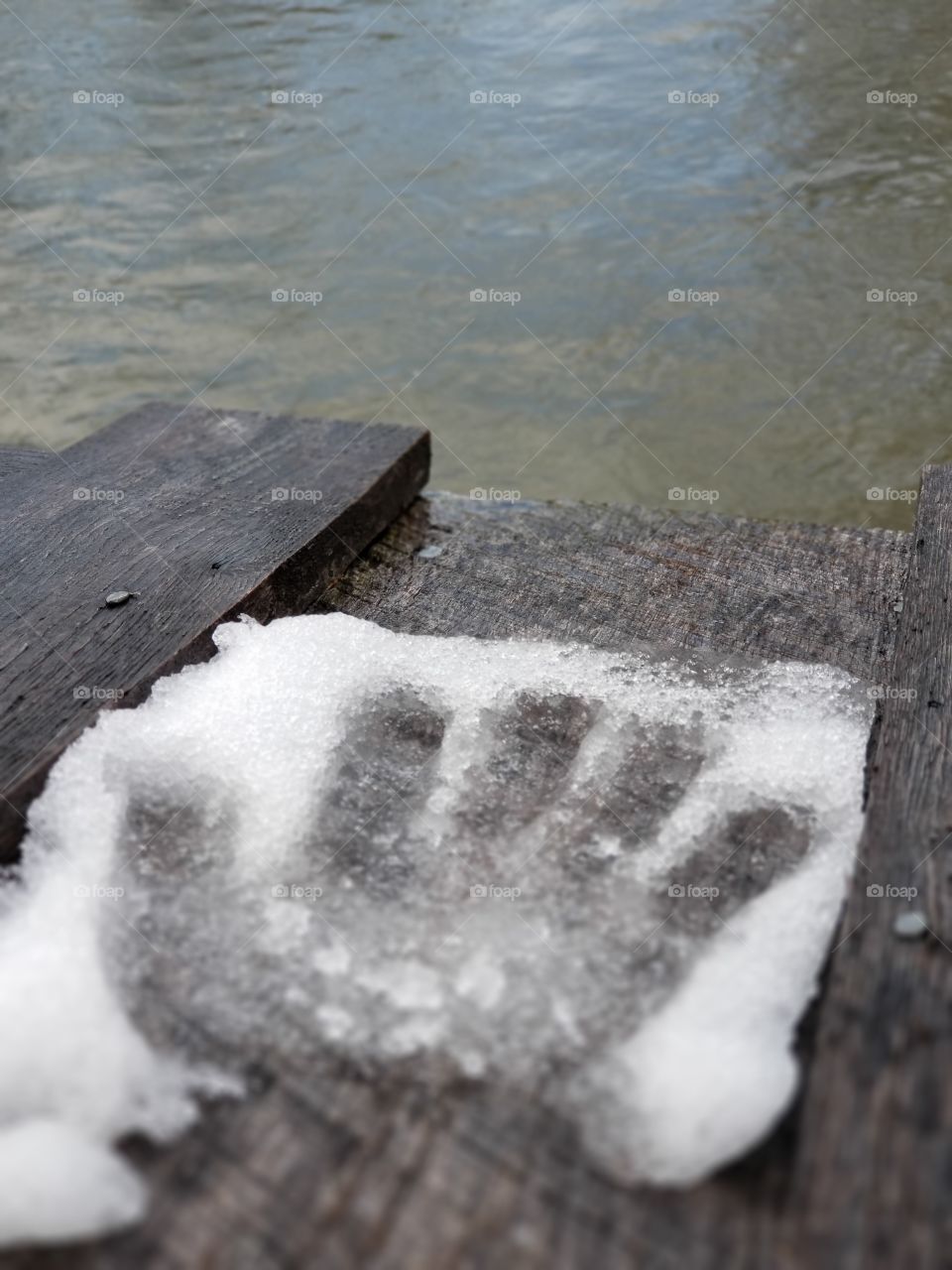 hand imprint in snow over water