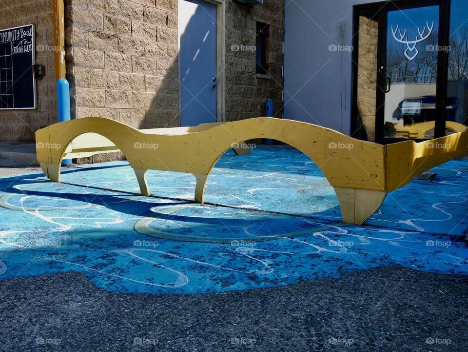 A pair of giant yellow sunglasses sitting in a painted pool of water. 
