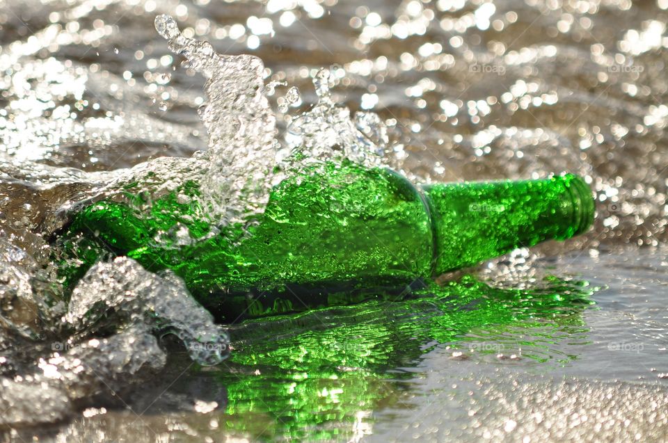Green wine bottle in water