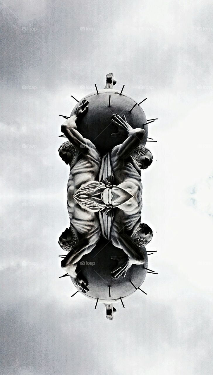 the weight of the world. reflected statue of two men carrying a heavy steel ball