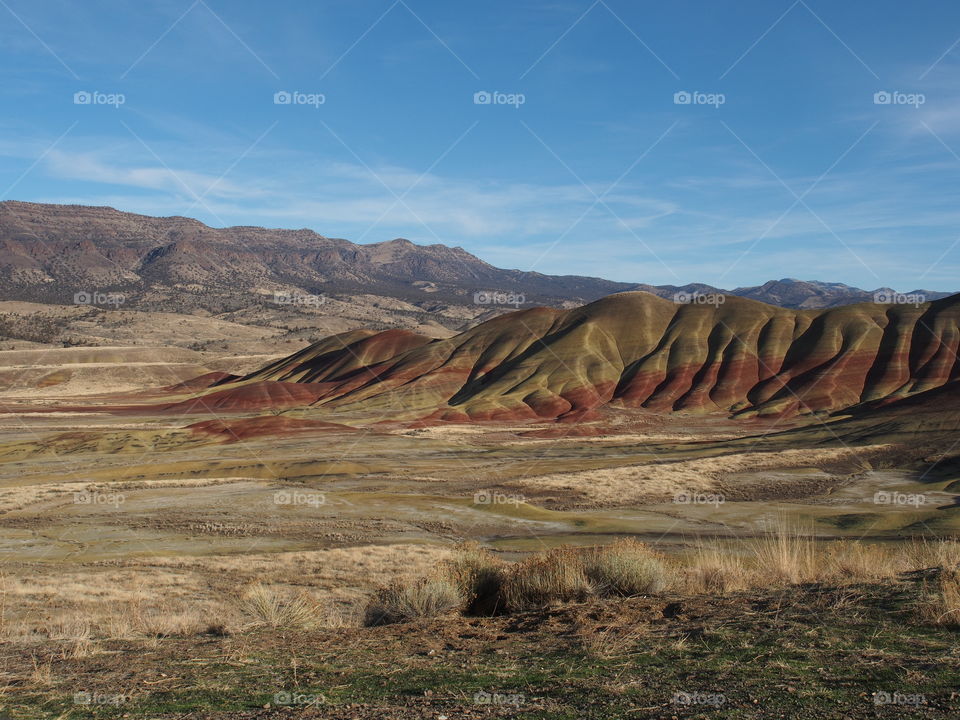 The incredible beauty of the red, gold, and browns of the textured Painted Hills in Eastern Oregon on a bright sunny day.