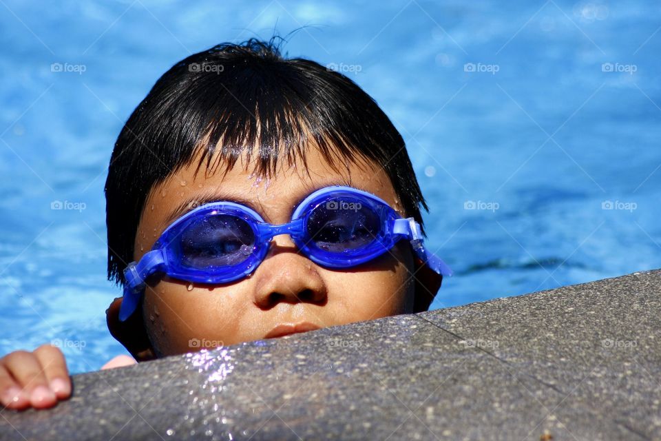 young boy with goggles in a swimming pool