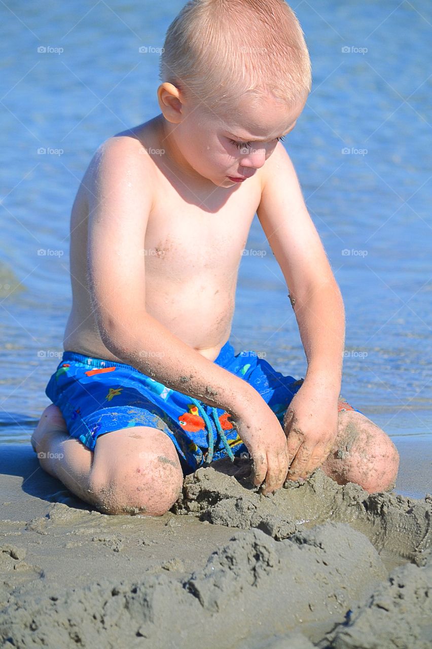 Boy digs in the beach sand