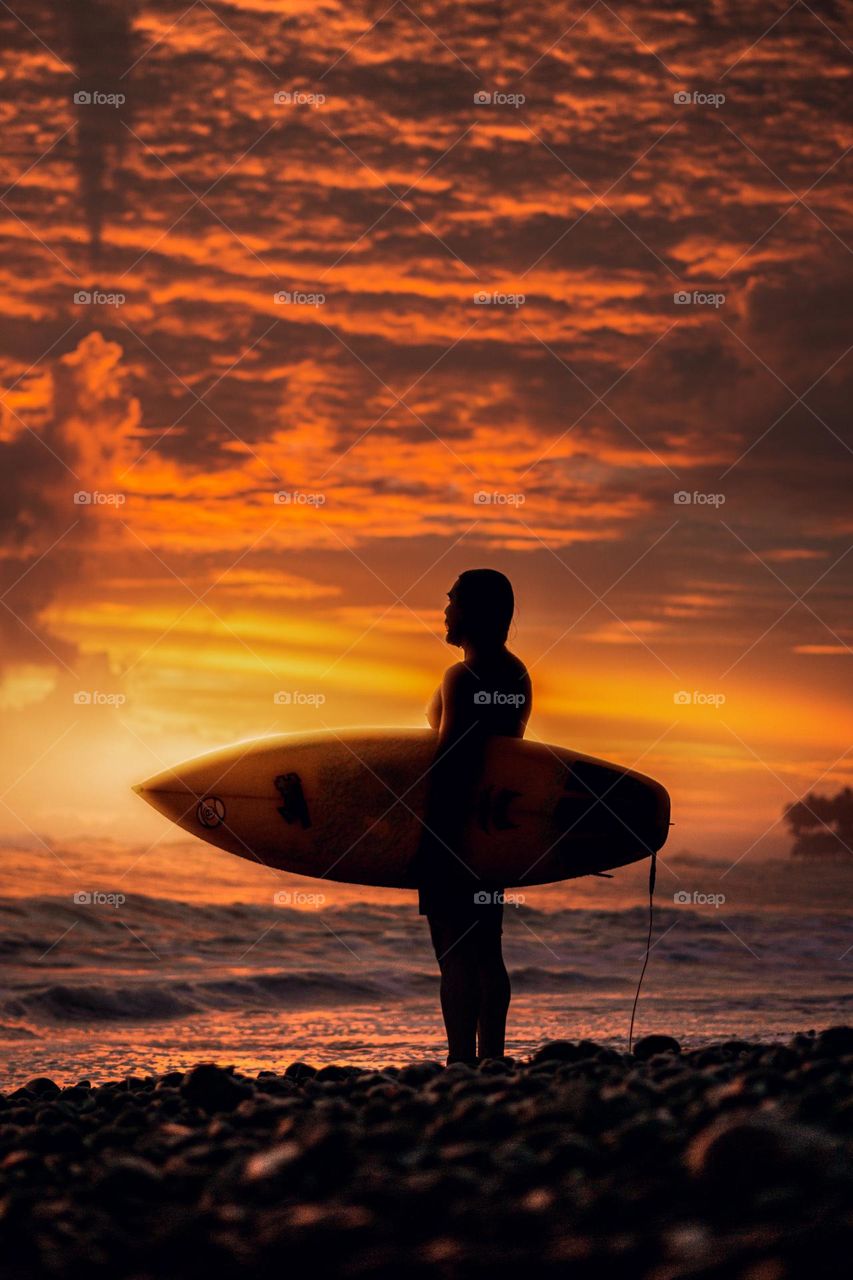 Beautiful sunset on a beach in Costa Rica, with the silhouette of a surfer watching the landscape