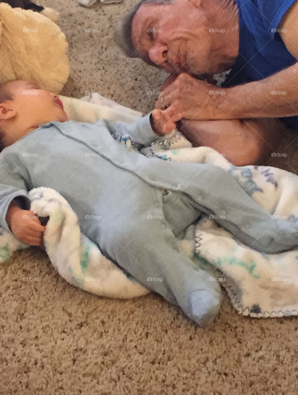 Grandpa and baby nor grandson lying on the floor playing.