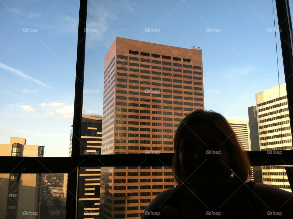 Silhouette of woman in window with city background.