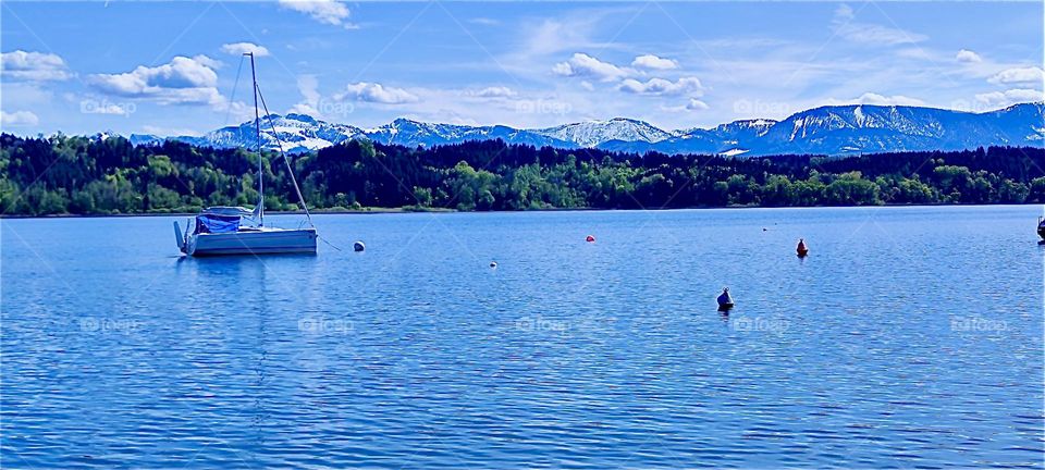 This is one of several lakes in the vicinity of „Bayerischzell“, a small town near the Alps in „Bavaria“, Germany. Across the water we see forested hills and iced over glaciers. 2024. Hypnotic Productions 