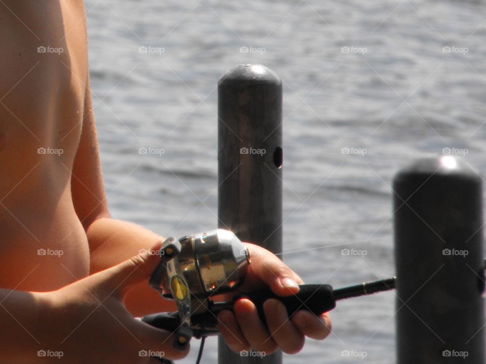 Young boy holding a fishing rod and reel at a lake