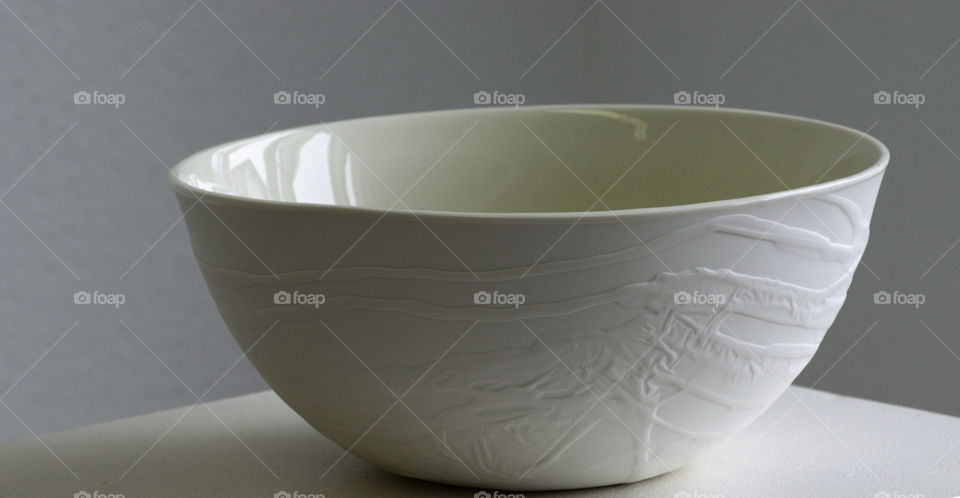 Beautifuĺly designed white porcelain bowl standing on a white stand. Clean and simple design closeup.