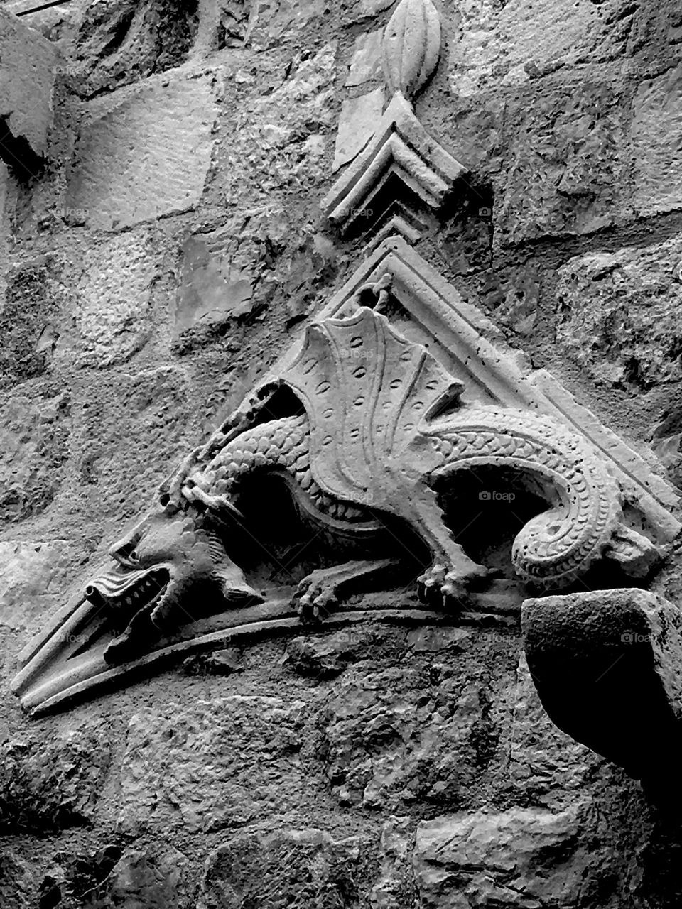 Creepy black and white dragon demon on stone wall.