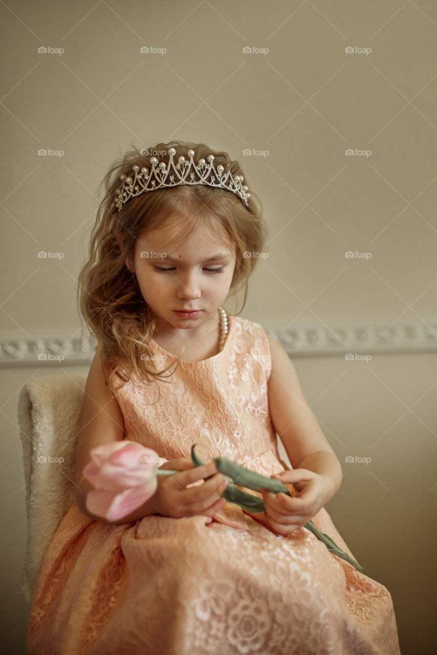 Vintage portrait of a beautiful little girl in pearl crown with tulip flower