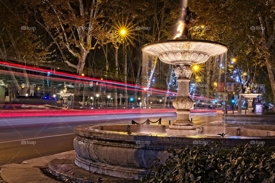 Traffic light trails and illuminated fountain in the city
