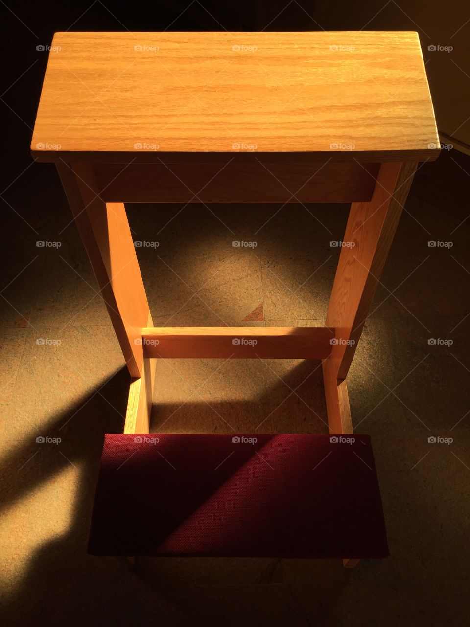 Prayer bench with a splash of light from a nearby stained glass window.