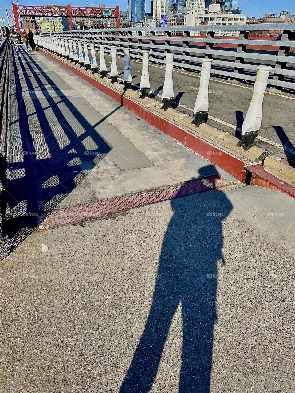 The shadows cast onto the “Pulaski Bridge” at “Newtown Creek” that connects “Greenpoint”, Bklyn to LIC, Queens can be quite interesting such as this elongated slightly askew impression of myself, the photographer. 2023. Hypnotic Productions