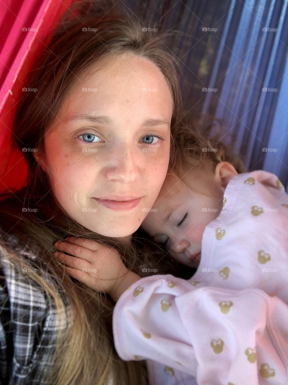 A mother holds her sleeping child while lying in a hammock