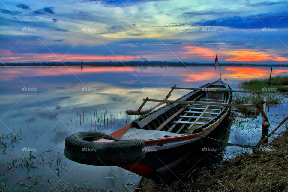 Alone boat under sunset at Galuh Cempaka Lake, Banjarbaru, Indonesia.