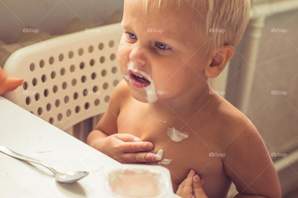 little boy is eating yogurt messily