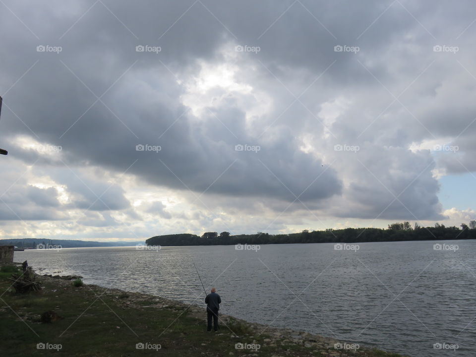 Cloudy sky and lonely fisherman