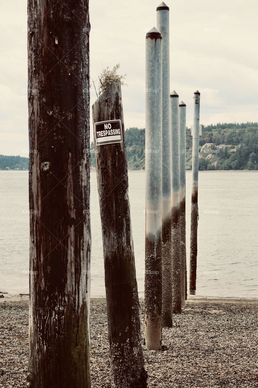 The no trespassing sign perched on an old dock piling shows signs of wear as the tide rolls out from Titlow Beach, Washington 
