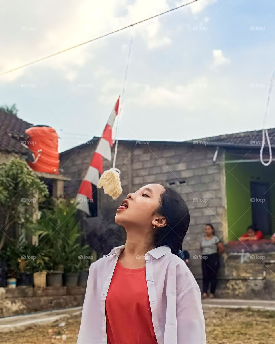 Portrait of a young woman taking part in a cracker eating competition on Indonesia's independence day