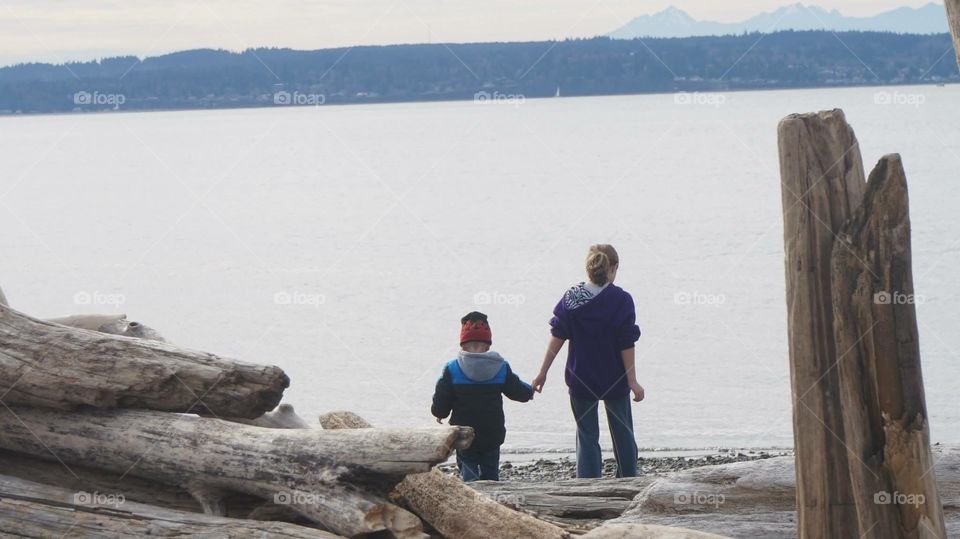 Best friends and family. A little boy following the lead of his best friend for a walk on the ocean shore