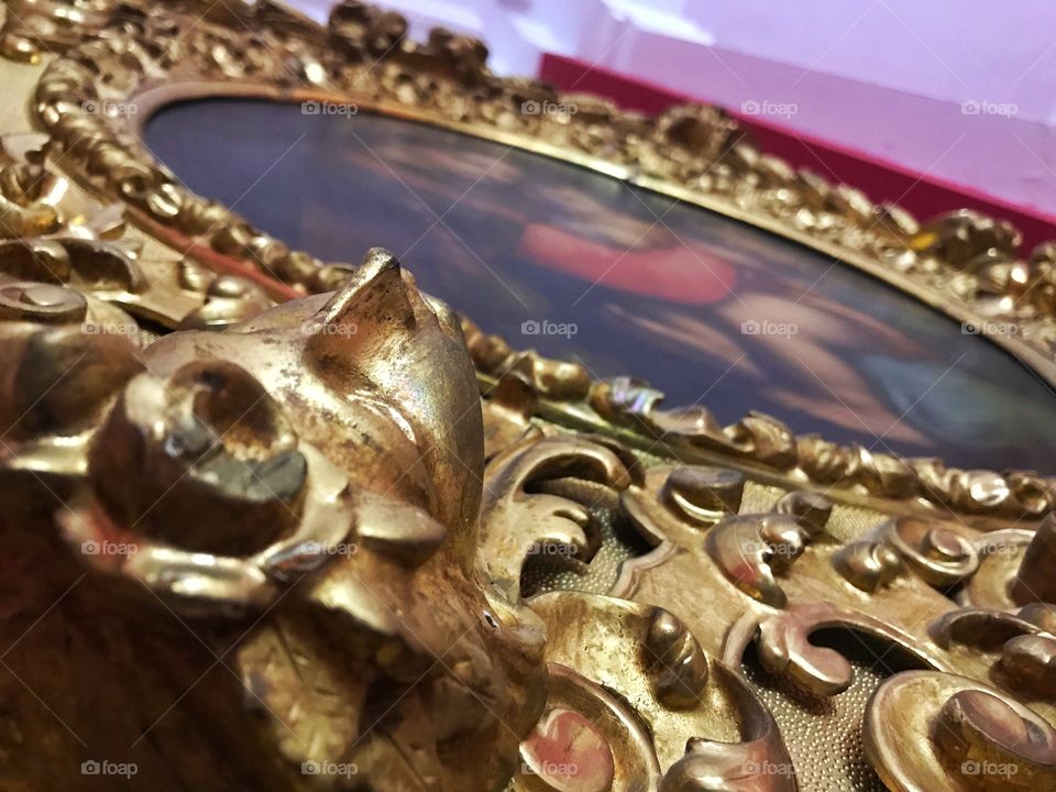 Detail of ornate carved golden frame. Close up view showing round frame in perspective 