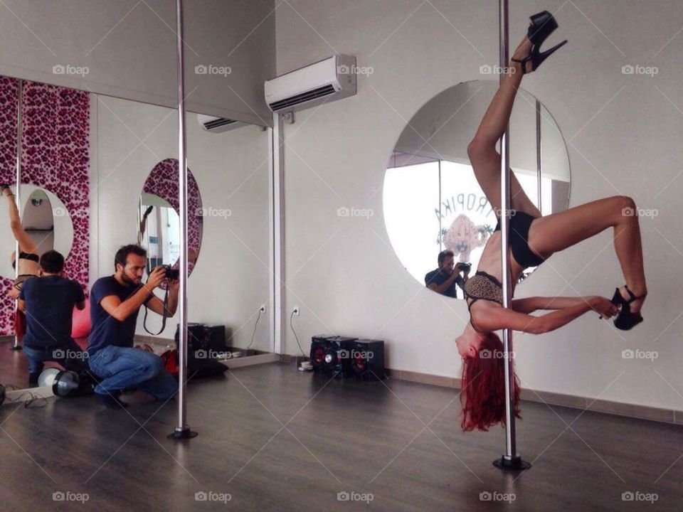 Man taking photograph of a pole dancer with camera