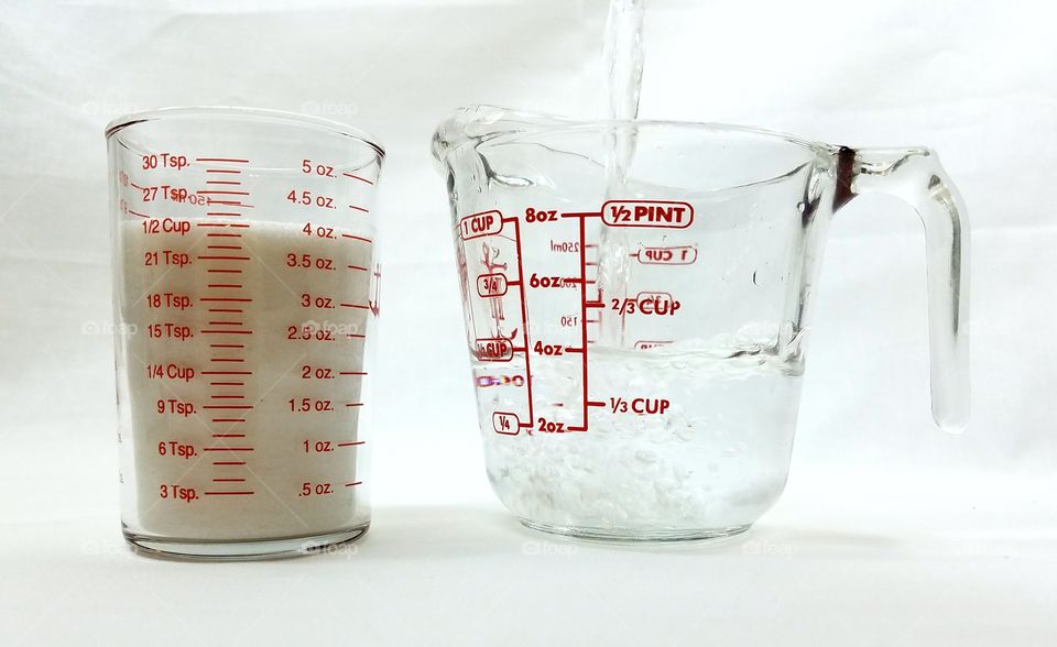measuring cups with sugar amd water pouring