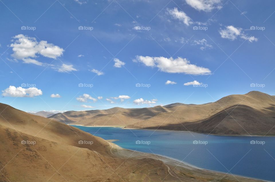 beautiful mountain lake in tibet - lake surrounded with mountains under cloudy sky