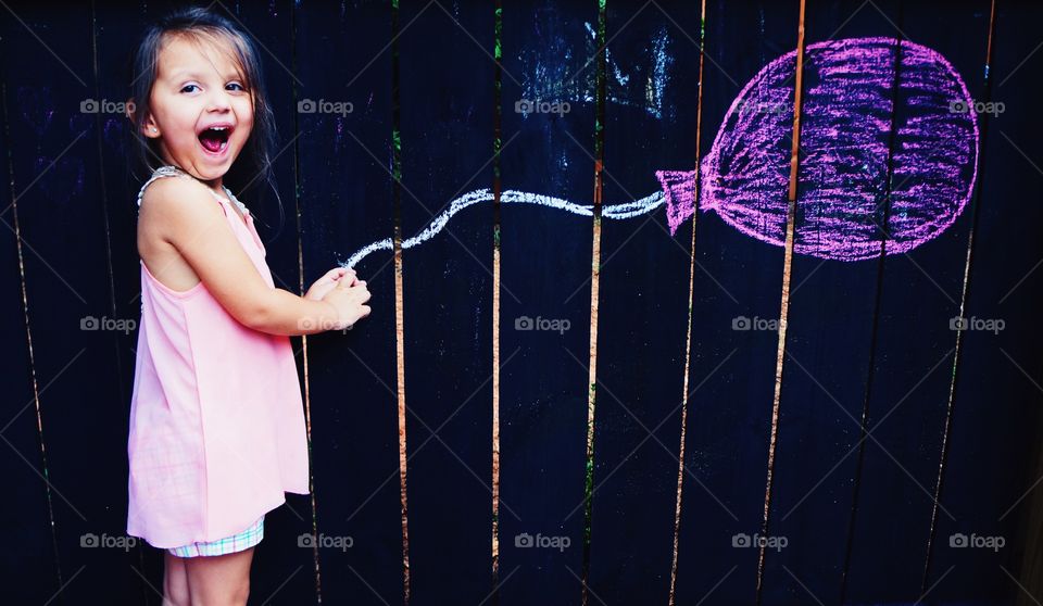 Little girl playing with drawing of balloon