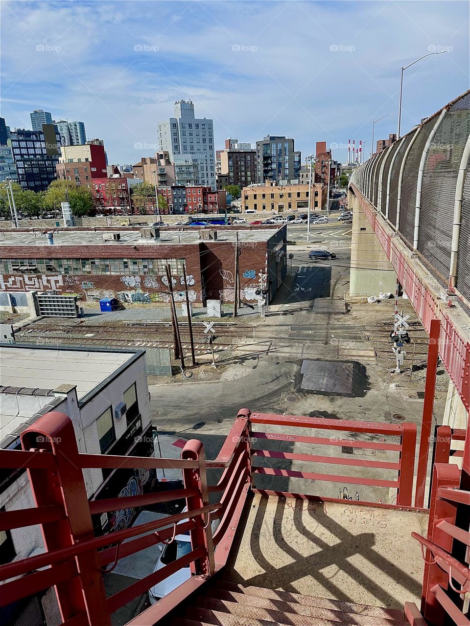 The orange red of the staircase and support structures of the “Pulaski Bridge” in LIC and the orange glow of the pavement evoke adjacent complementary overtones of blue in the shadows that repeat in the sky above. 2025. Hypnotic Productions