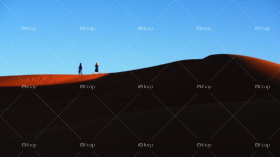 Desert Trek . two figures trek through the Sahara Desert, North Africa 