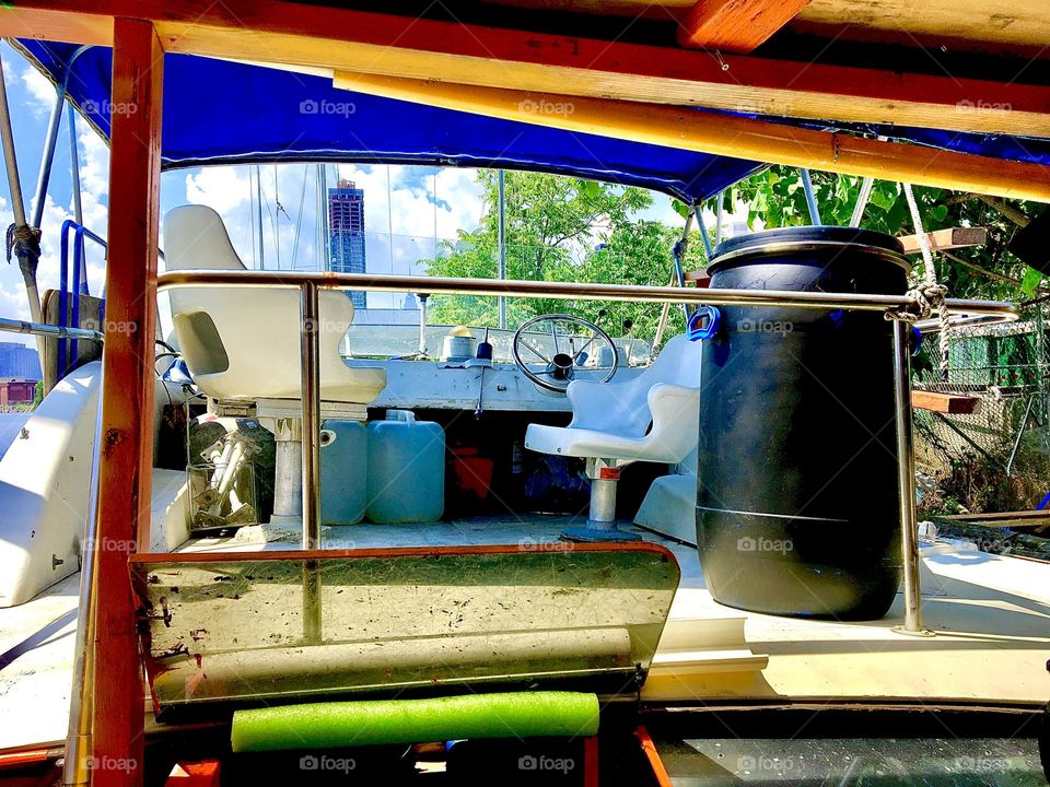 The upstairs deck of the “Salvation”, our boat at Newtown Creek in LIC, Queens, NY and the 25 gallon drum that contains our “shower water” seen from below on the back deck. A ladder leads upstairs on the far left. 2021. Hypnotic Productions