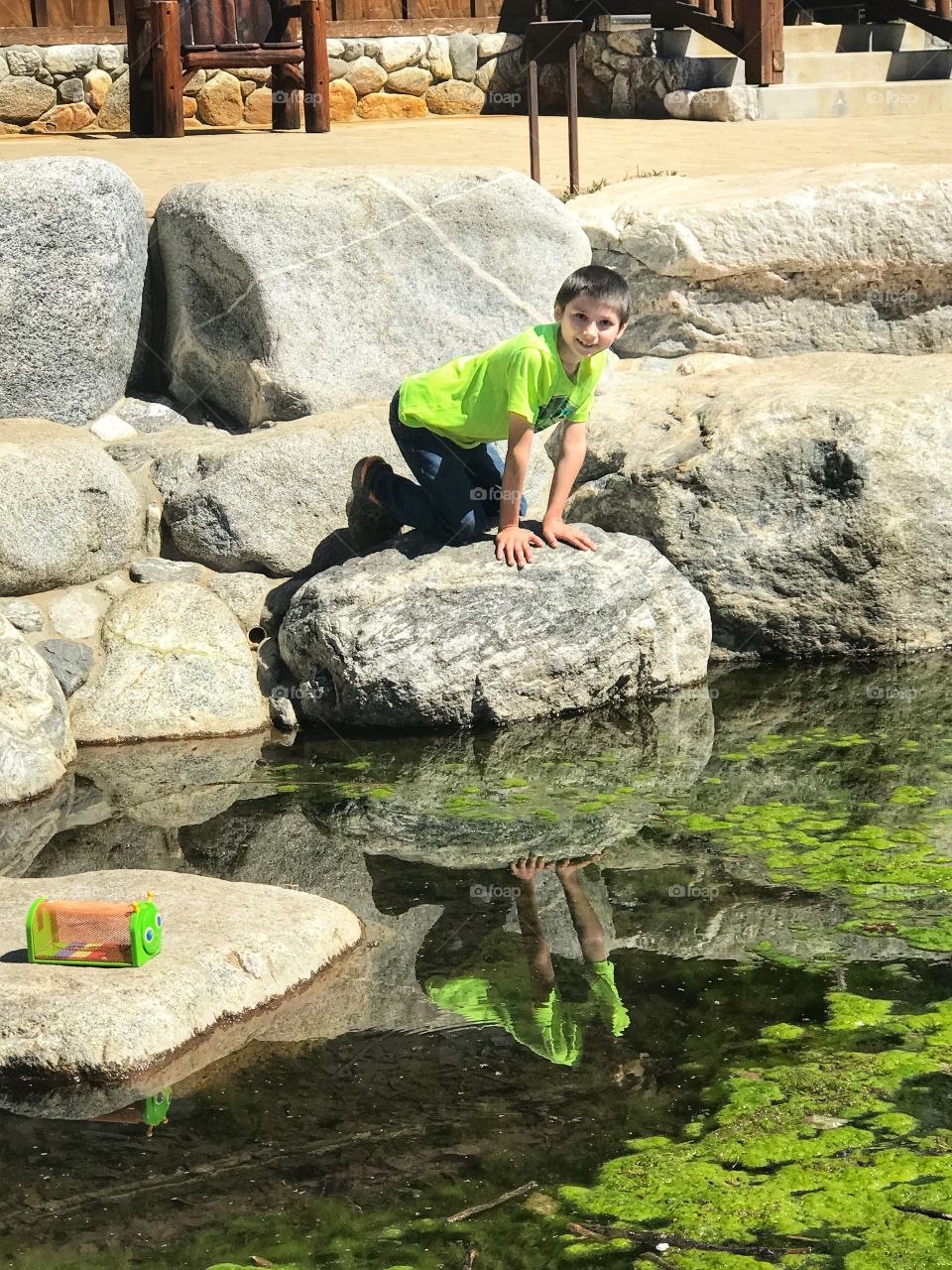 Little boy on a rock at the pond