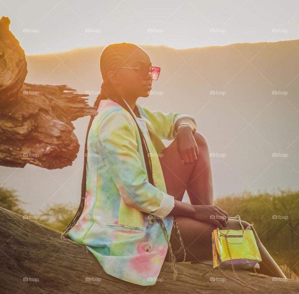 a woman sitting on wood during sunset