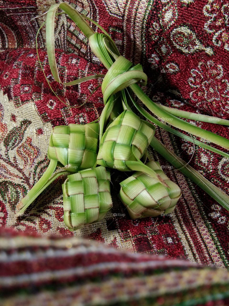 ketupat on prayer rug. ketupat made from woven coconut leaves, filled with rice before cooking. traditional food from Indonesia on Ramadan and Eid Al-Fitr