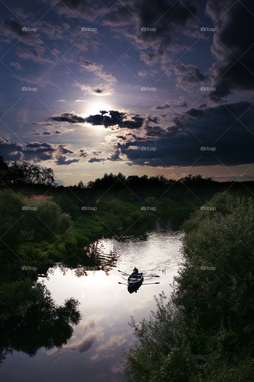 Day and night. River boatman. Sunset over the river