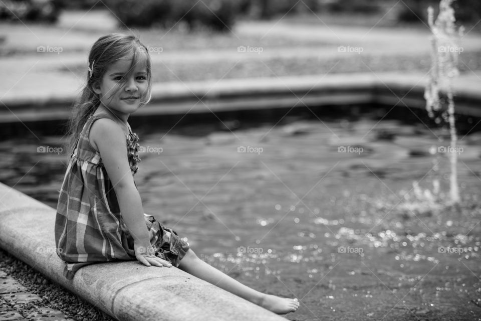 Portrait of little girl sitting on edge
