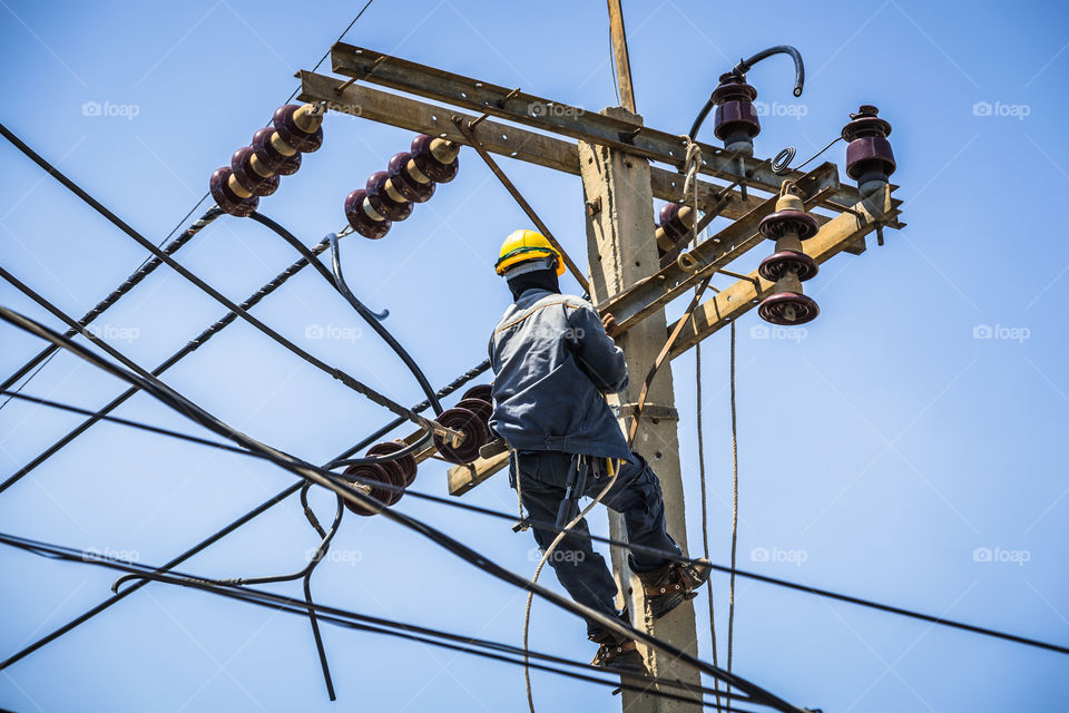 Electrician working on the electricity pole to replace the electrical insulator