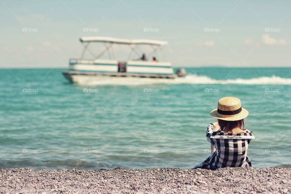 Girl on the beach looking at the boat
