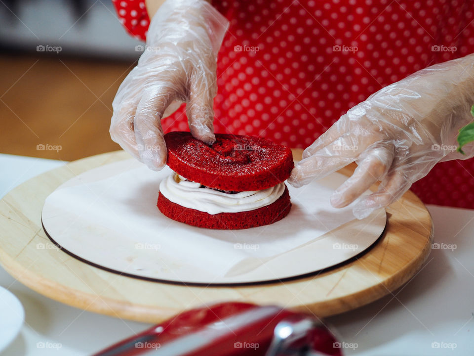Woman confectioner in red dress making rad velvet cake