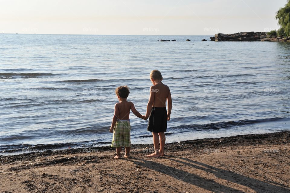 Brothers holding hands by the lake